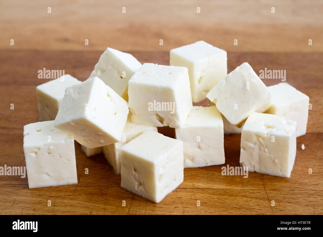 Cubes carrés de fromage féta isolé sur bois board avec couteau. Banque D'Images