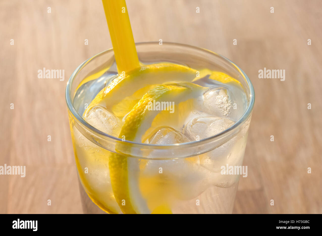 Verre simple d'eau glacée avec les tranches de citron et de la paille sur une table. Banque D'Images