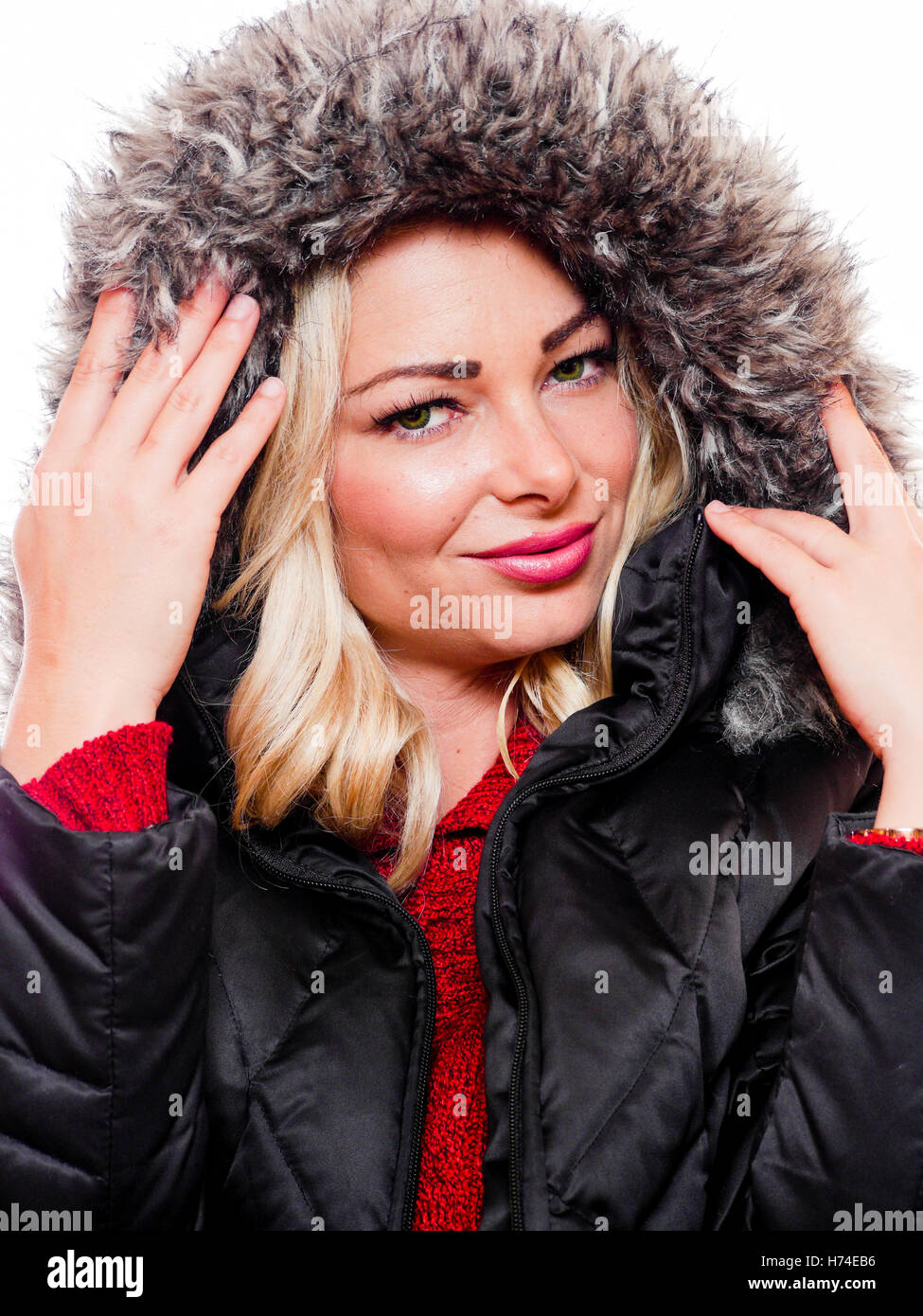 Une jolie femme est photographié portant un manteau d'hiver avec le capot sur un fond blanc. Banque D'Images