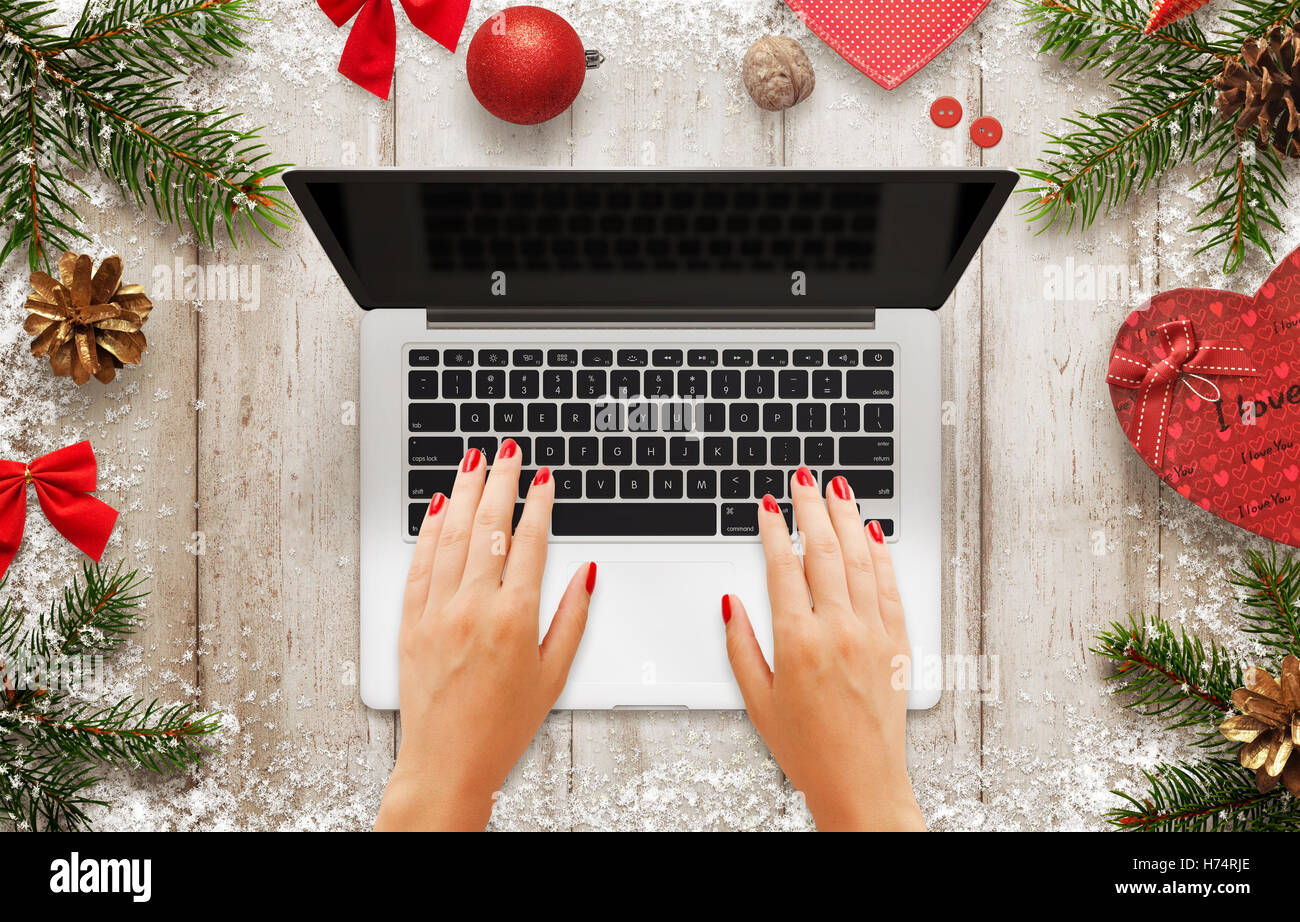 Travail sur ordinateur portable. Femme Scène de Noël avec des décorations, arbre et cadeau. Écran noir pour une maquette. Vue de dessus de table. Banque D'Images