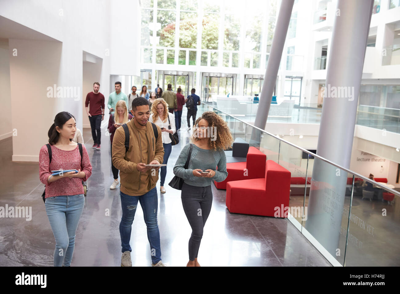 Les élèves marcher et parler à l'aide de périphériques mobiles à l'université Banque D'Images