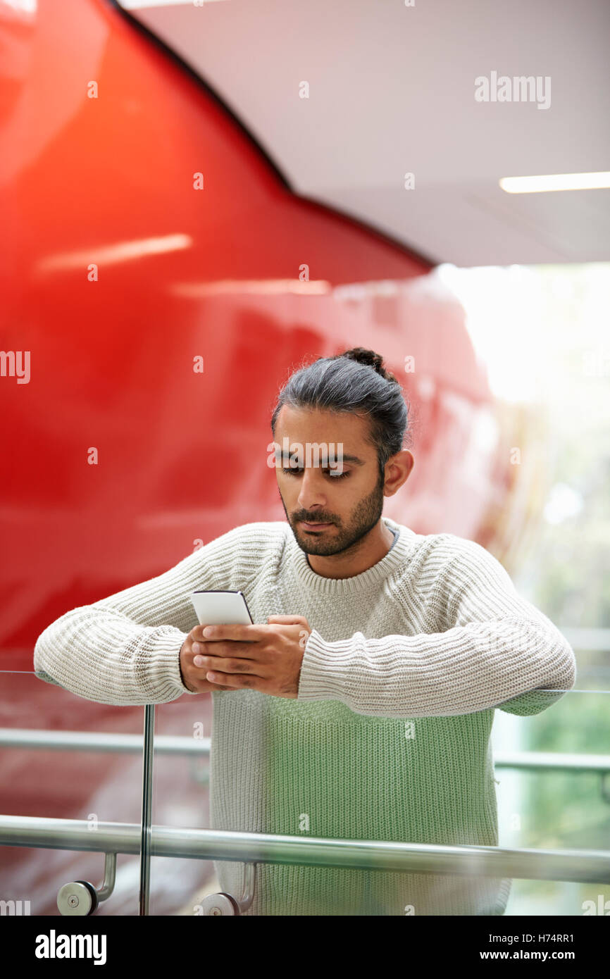 Asian male university student using smartphone, vertical Banque D'Images
