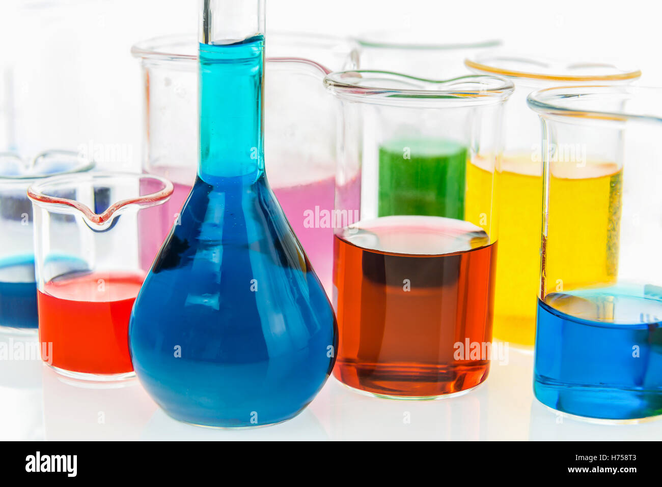 Ballon jaugé et divers bols avec différents types d'indicateurs dans les acides et les bases, quatre couleurs d'indicateurs dans plusieurs Banque D'Images