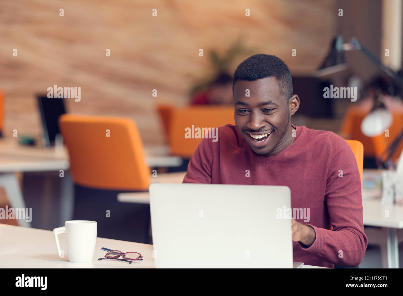 Jeune homme d'affaires avec une expression choquée de travailler sur un ordinateur portable Banque D'Images