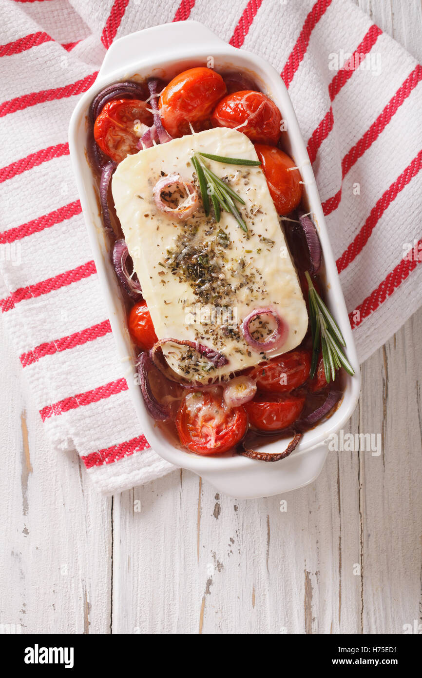 La nourriture grecque : Feta au four avec tomates et oignons dans le plat de cuisson. vertical Vue de dessus Banque D'Images
