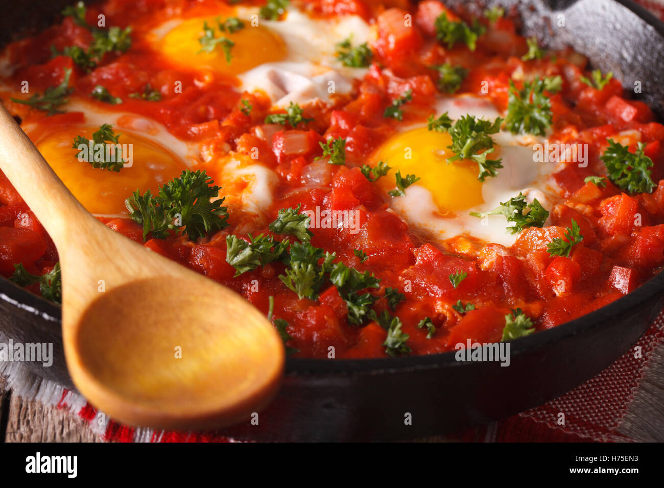 Hôtes shakshuka oeufs au plat avec la sauce tomate dans la casserole horizontale de macro. Banque D'Images