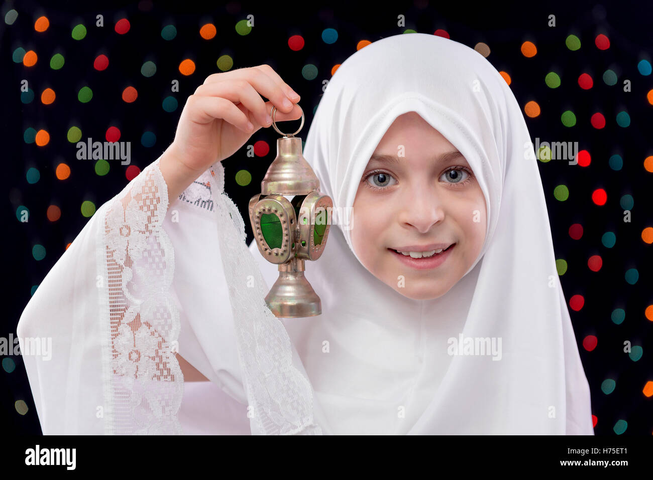 Jeune musulmane en blanc Hijab Holding Ramadan lanterne sur Nuit Lumières Fond flou artistique Banque D'Images