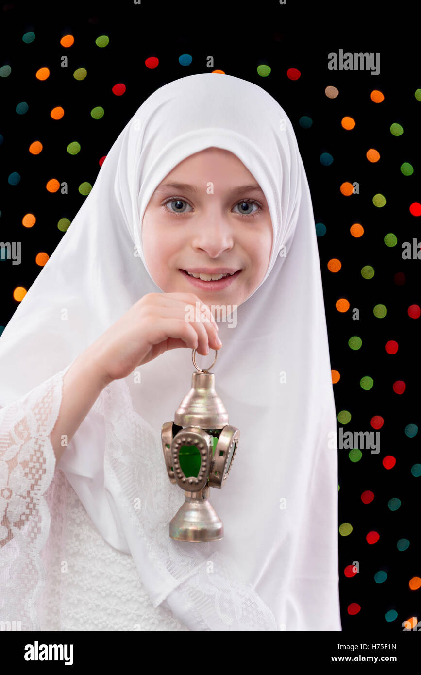 Belle jeune fille musulmane en blanc Hijab Holding Ramadan lanterne sur Nuit Lumières Fond flou artistique Banque D'Images
