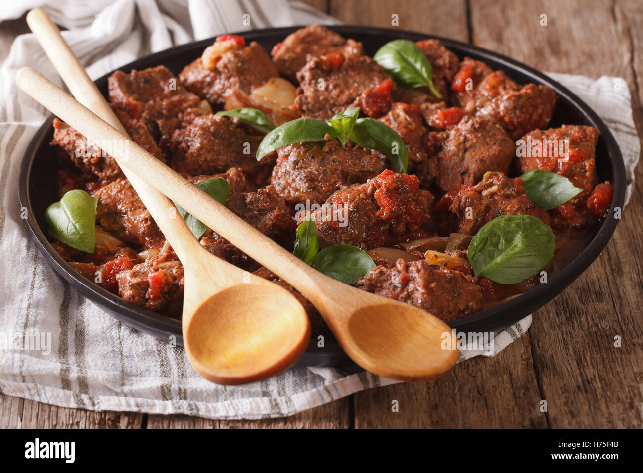 De délicieux plats grecs : boeuf avec sauce stifado et basilic close up dans un plat sur la table horizontale. Banque D'Images