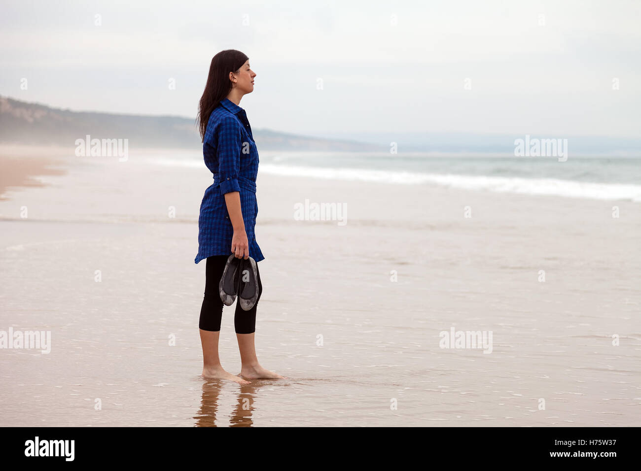 Seul et déprimé femme regardant la mer dans une plage déserte sur une journée d'automne. Banque D'Images