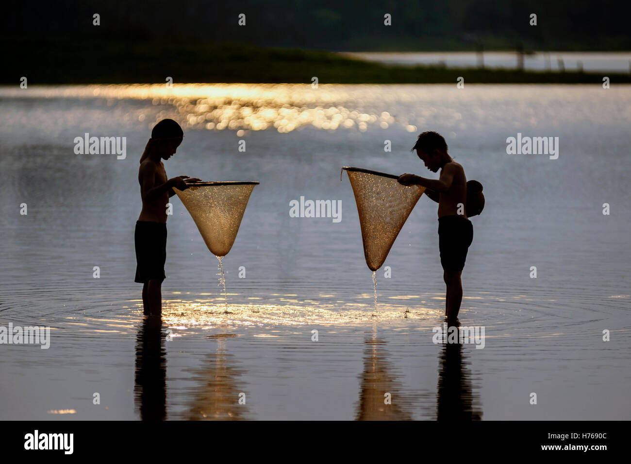 Silhouette de deux garçons au coucher du soleil, pêche Banque D'Images