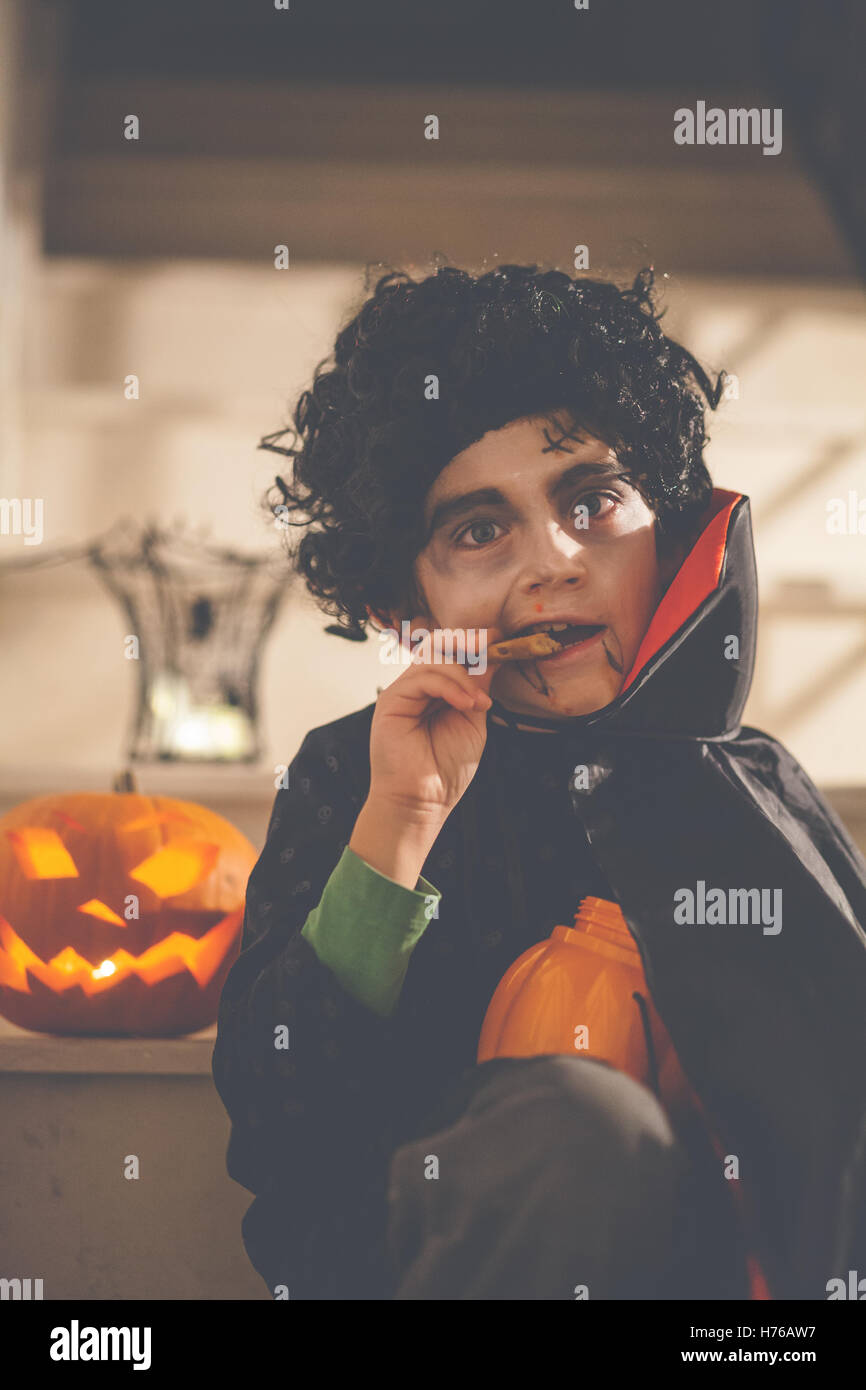 Garçon habillé en costume Halloween Dracula de manger un cookie Banque D'Images