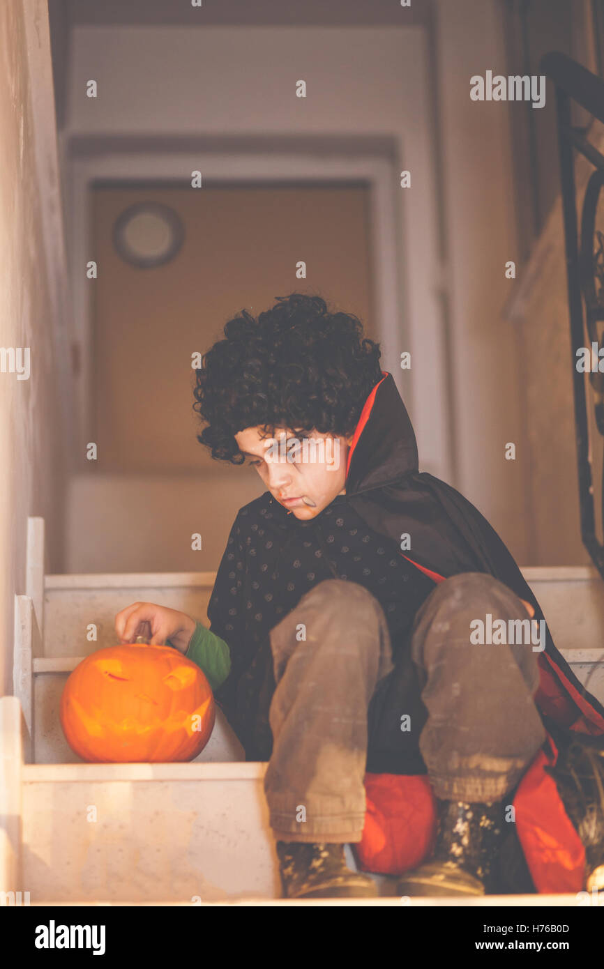 Garçon en costume dracula halloween assis sur les marches à l'aide d'un cric-o-lanterne Banque D'Images