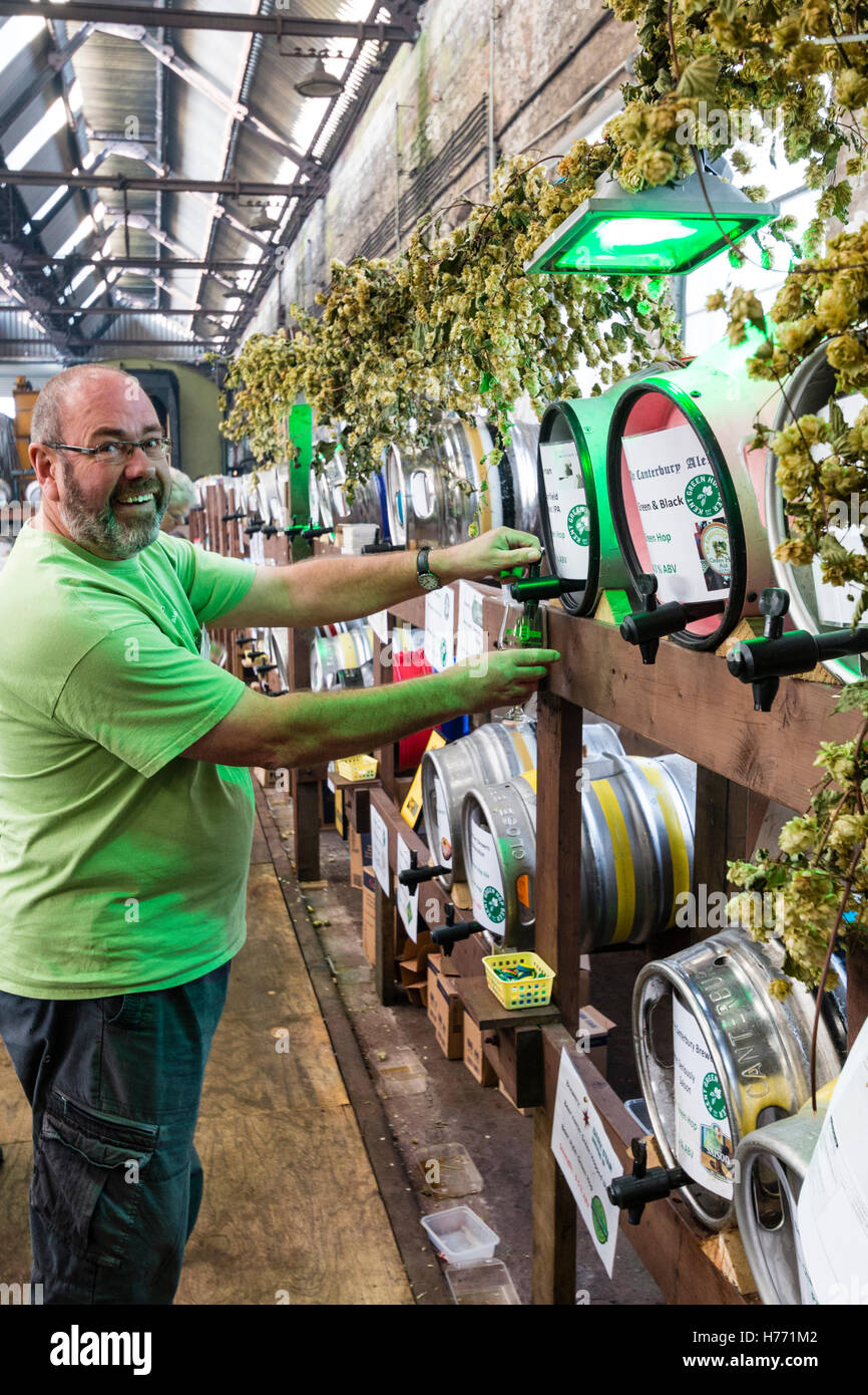 L'Angleterre, Tunbridge Wells. La bière et l'ale CAMRA festival. Couple et verser une pinte de bière du corps, entre les rangées de fûts de bière différentes. Banque D'Images