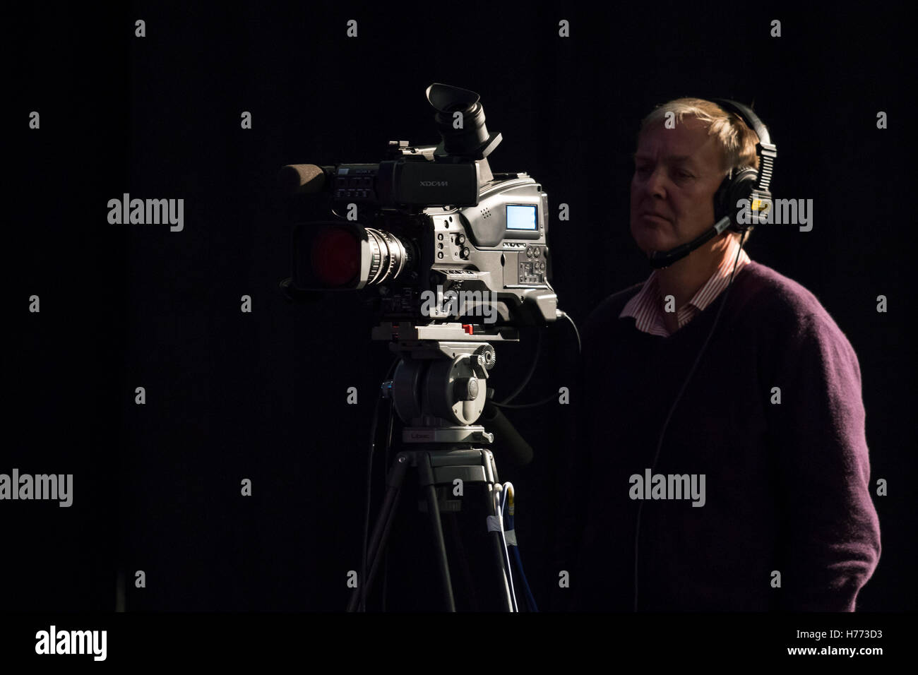 Un caméraman de télévision diffusées à l'aide de sa caméra pour enregistrement tv vu sur un fond noir. Banque D'Images