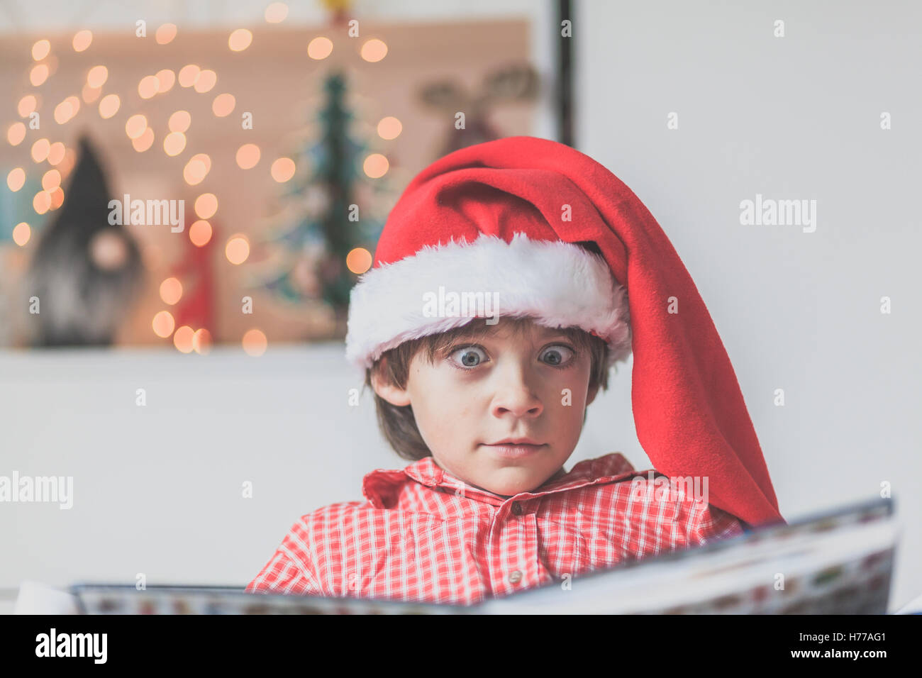 Portrait of a Boy reading in a christmas santa hat Banque D'Images