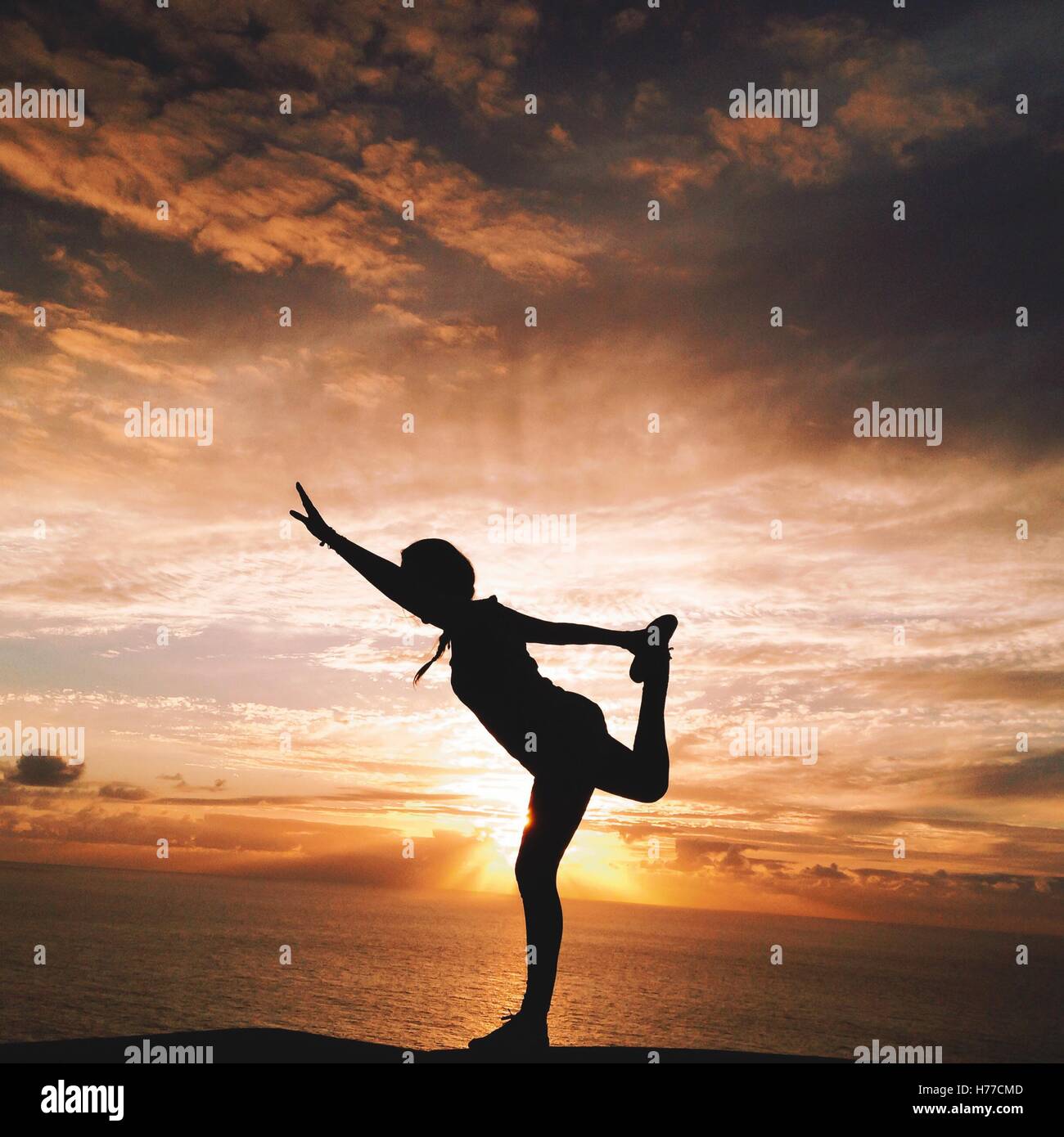Silhouette d'une femme faisant du yoga sur la plage au coucher du soleil Banque D'Images Silhouette d'une femme faisant du yoga sur la plage au coucher du soleil Banque D'Images
