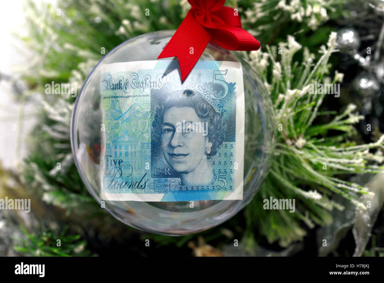 Une note de cinq livres dans une boule de noël sur un arbre. Banque D'Images
