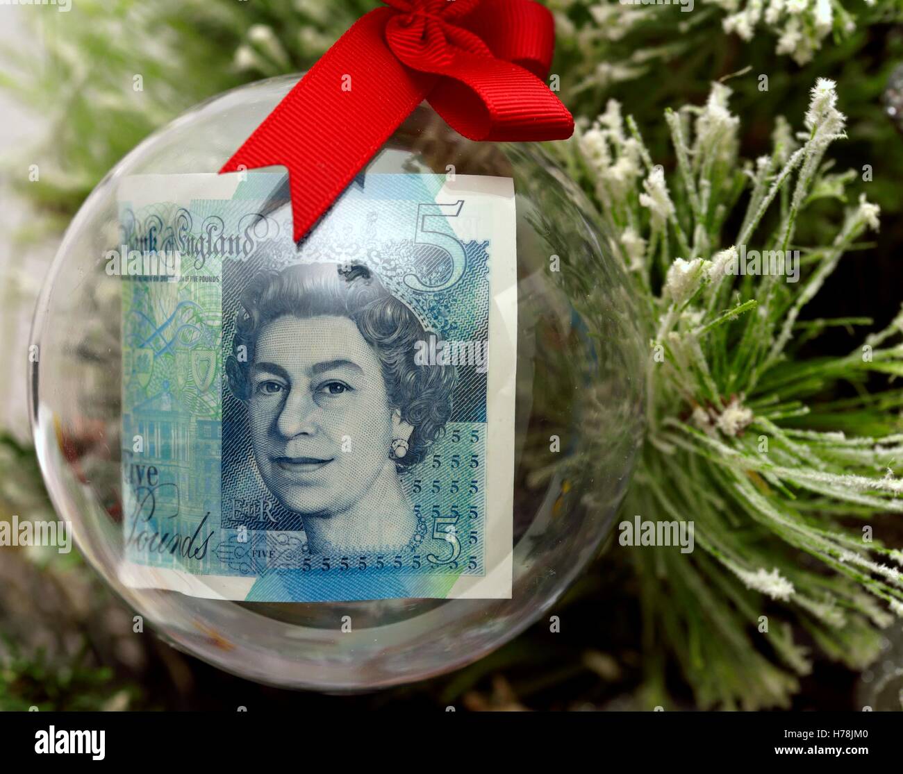 Une note de cinq livres dans une boule de noël sur un arbre. Banque D'Images