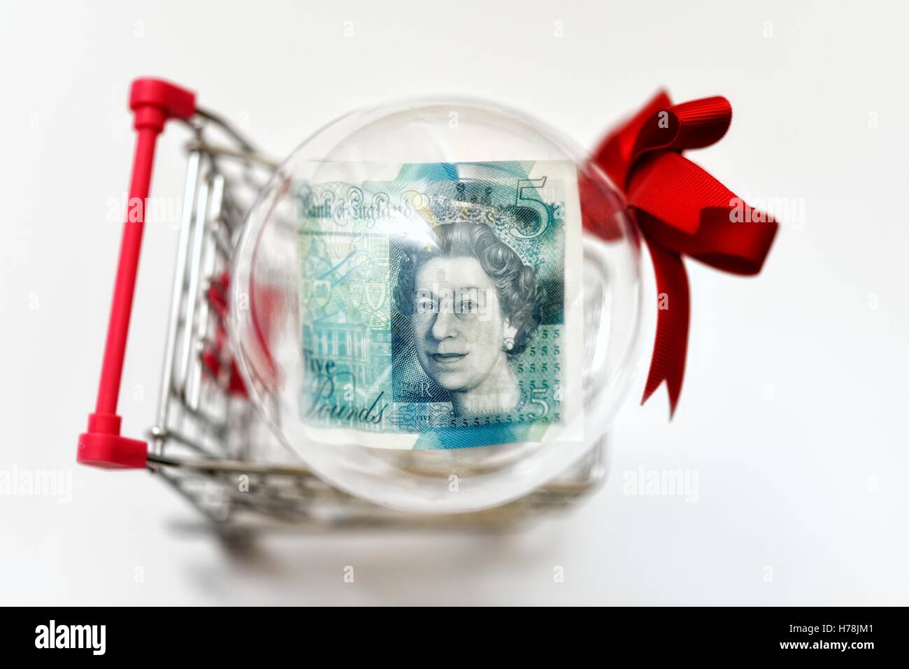 Une note de cinq livres dans une boule de Noël dans un panier. Banque D'Images