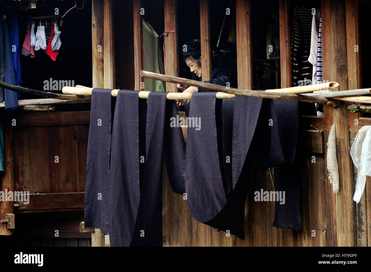 Femme s'étend sur la ceinture noire de sa robe, depuis le balcon de sa maison dans un village à l'ouest de Zhaoxing Banque D'Images