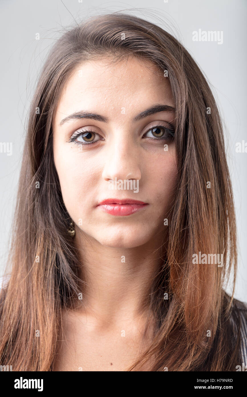 Young attractive brunette femme aux longs cheveux de longueur d'épaule à directement à l'objectif dans un close up head shot Banque D'Images