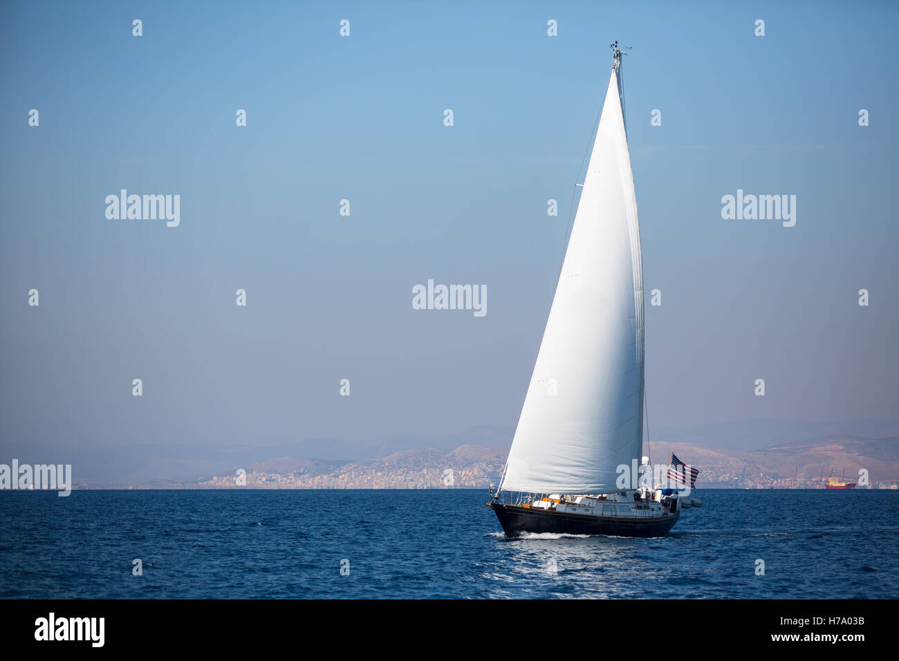 Yacht à voile avec voiles blanches dans le brouillard en mer près de la côte. Banque D'Images
