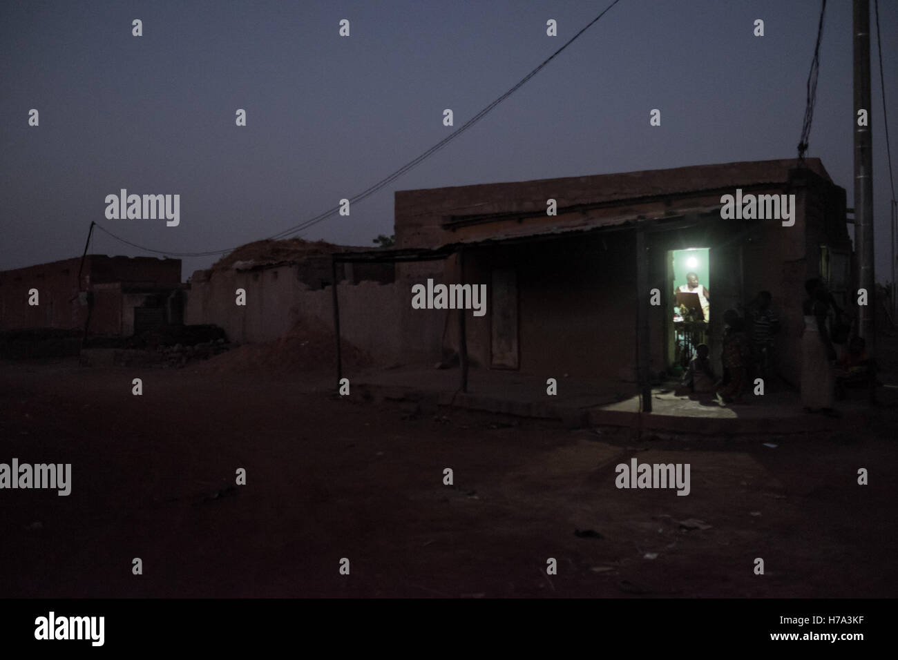 L'électrification rurale et de l'énergie solaire en Afrique subsaharienne. - 03/03/2016 - - M'pessoba (Mali), le 3 mars 2016. Rues de m'pessoba au crépuscule sombre est devenu très rapide. Traders connectés au réseau ou avec un équipement solaire sont en mesure de rester ouvert et de continuer à travailler même la nuit. Boutiques se sont facilement accessibles par les clients. - Nicolas Remene / Le Pictorium Banque D'Images