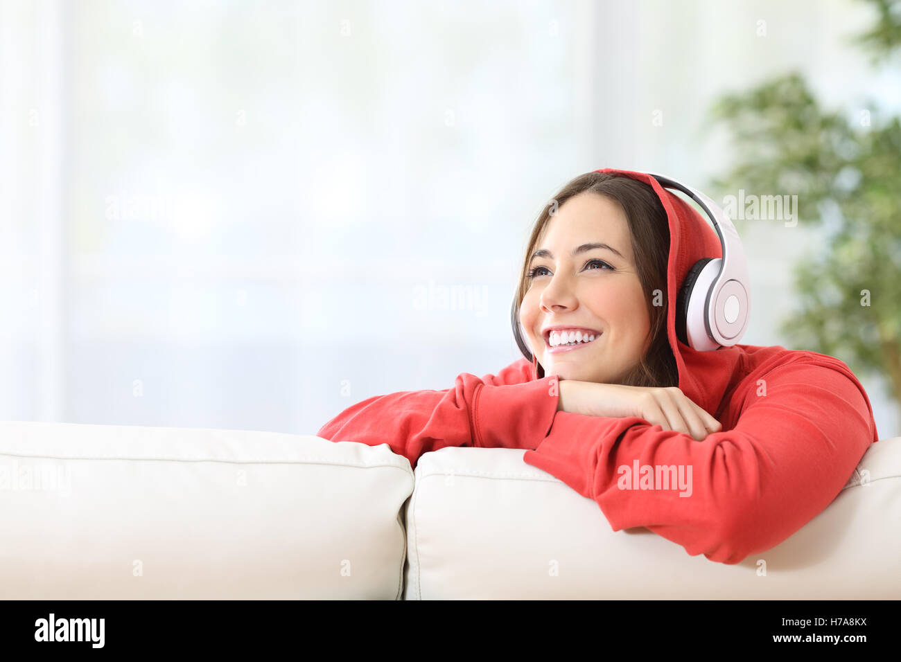 Dreamer girl à l'écoute de la musique avec le casque sur un canapé dans la salle de séjour à la maison et à ci-dessus avec copie espace Banque D'Images