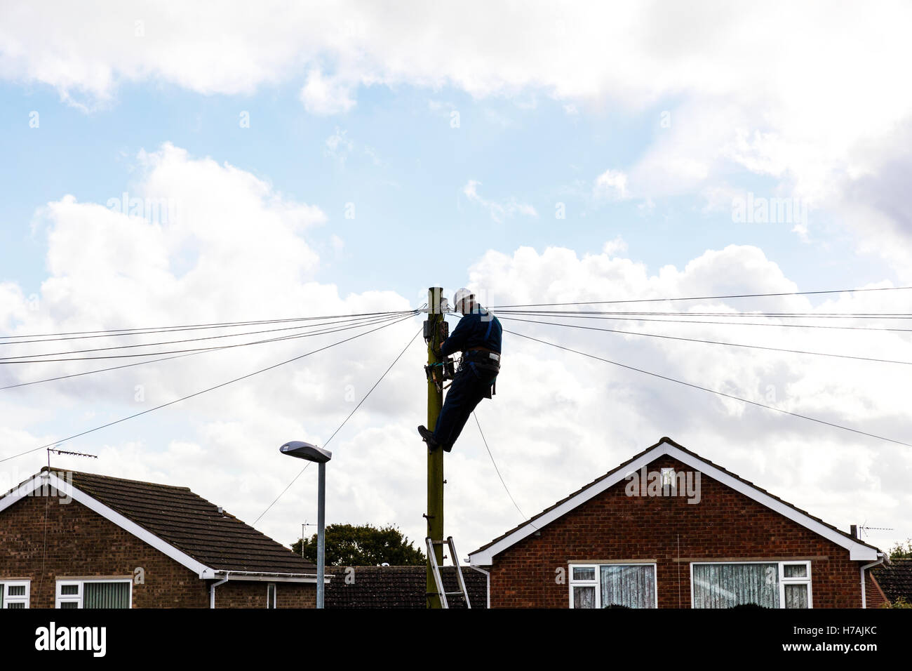 BT engineer repairing téléphone line up poteau télégraphique à la ligne de travail de réparation à large bande de l'homme Royaume-uni Angleterre GO pôle Banque D'Images