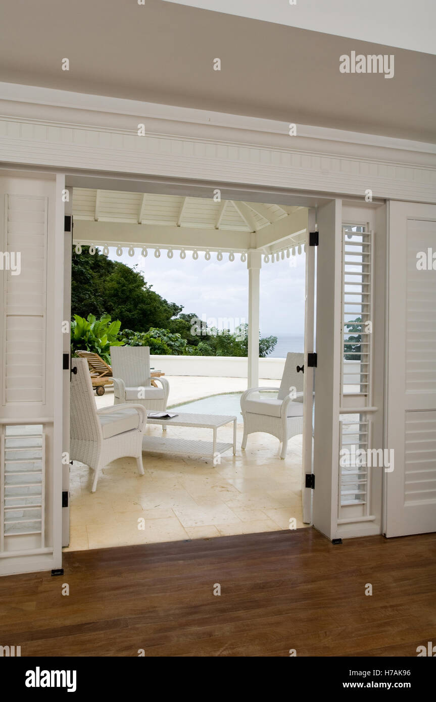 Vue à travers une fenêtre sur des meubles en rotin peint en blanc sur la  terrasse de St Lucia accueil, Caraïbes Photo Stock - Alamy