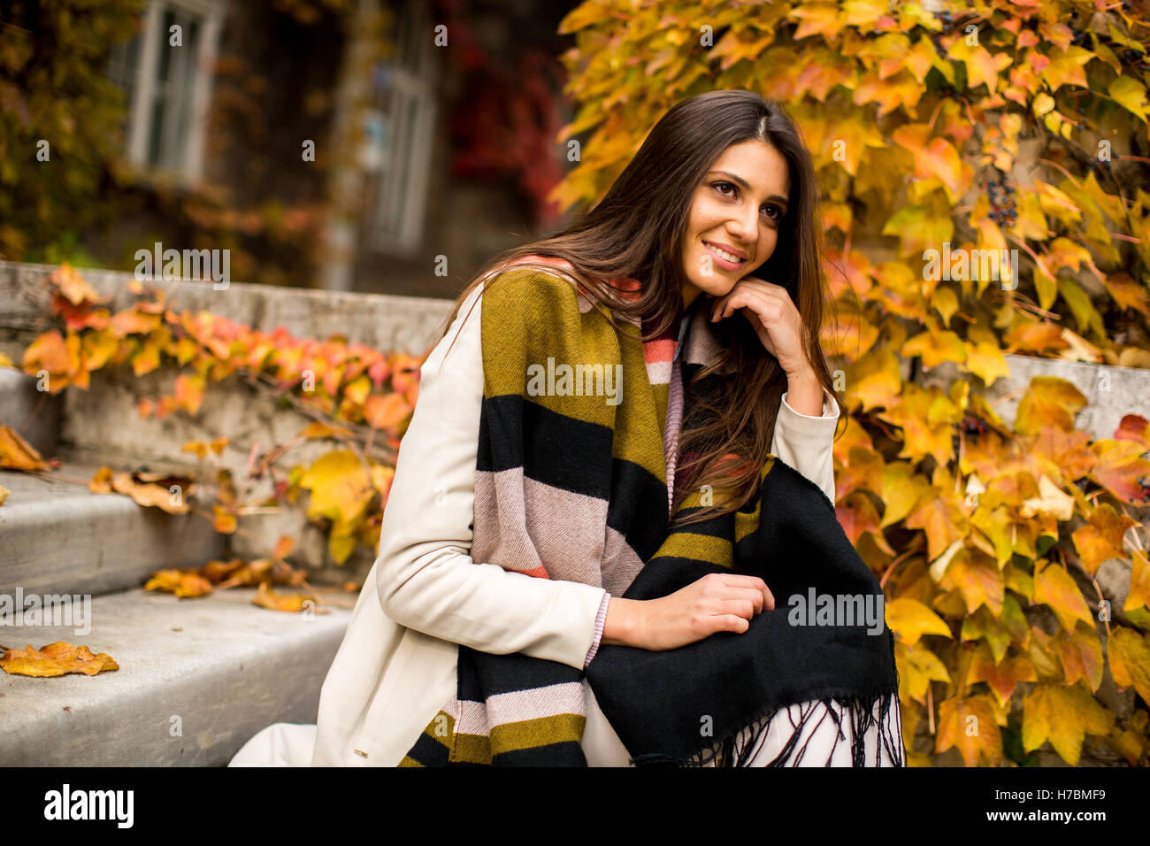 Jeune femme assise sur les marches à l'extérieur à l'automne 24 Banque D'Images