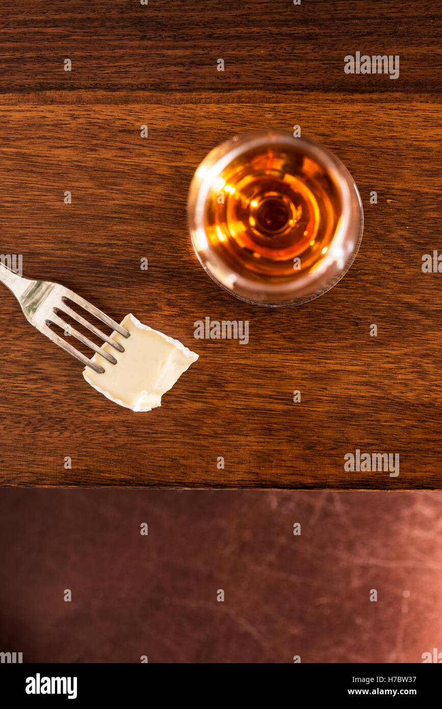 Dans un verre de sherry et un morceau de fromage brie sur une fourchette. Snack ou apéritif. Banque D'Images