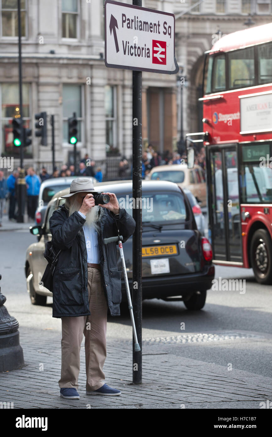 Personnes âgées était photographe de prendre des photos à Trafalgar Square, Central London, England, UK Banque D'Images
