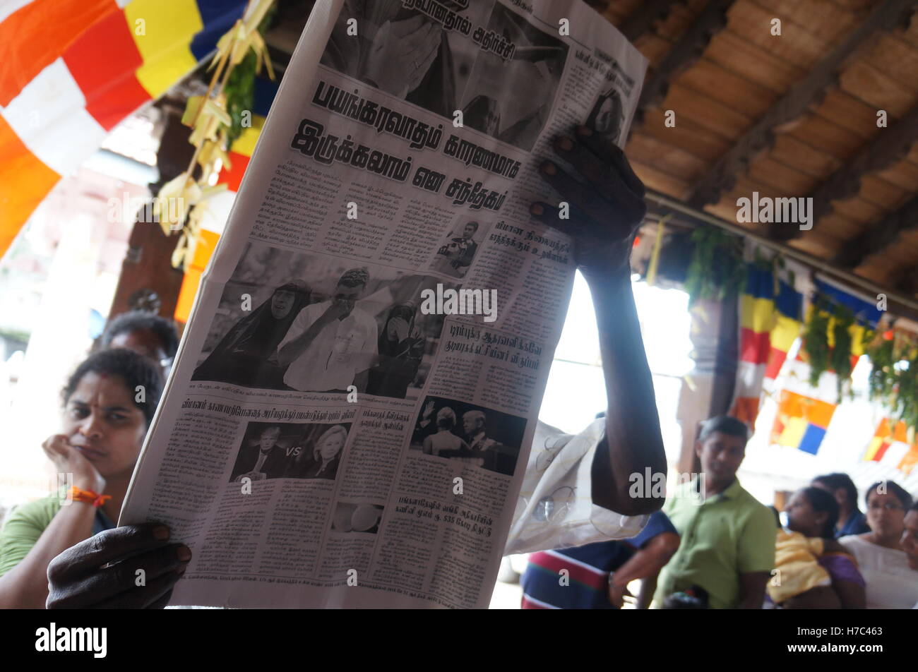 Un homme est en train de lire un journal, la queue pour de la nourriture gratuite dans un temple hindou à Kandy, Sri Lanka, le jour de la fête du Vesak. Banque D'Images