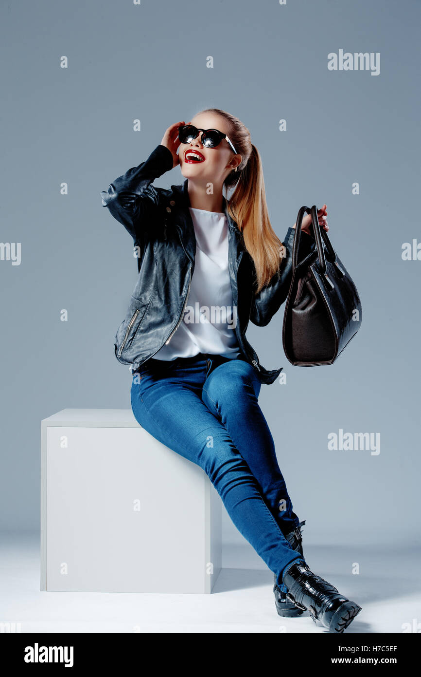 Fashion model sur white cube smiling dans lunettes de soleil Banque D'Images