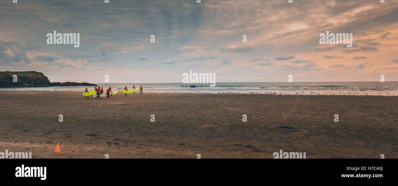 Les internautes novice sur une plage irlandaise sur le point d'aller dans de vagues avec leur instructeur au cours d'un beau coucher de soleil particulièrement Banque D'Images