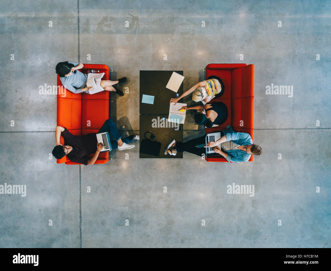 Jeunes assis autour d'une table et étudiant à la bibliothèque publique. étudiants universitaires avec livres et ordinateur portable Banque D'Images