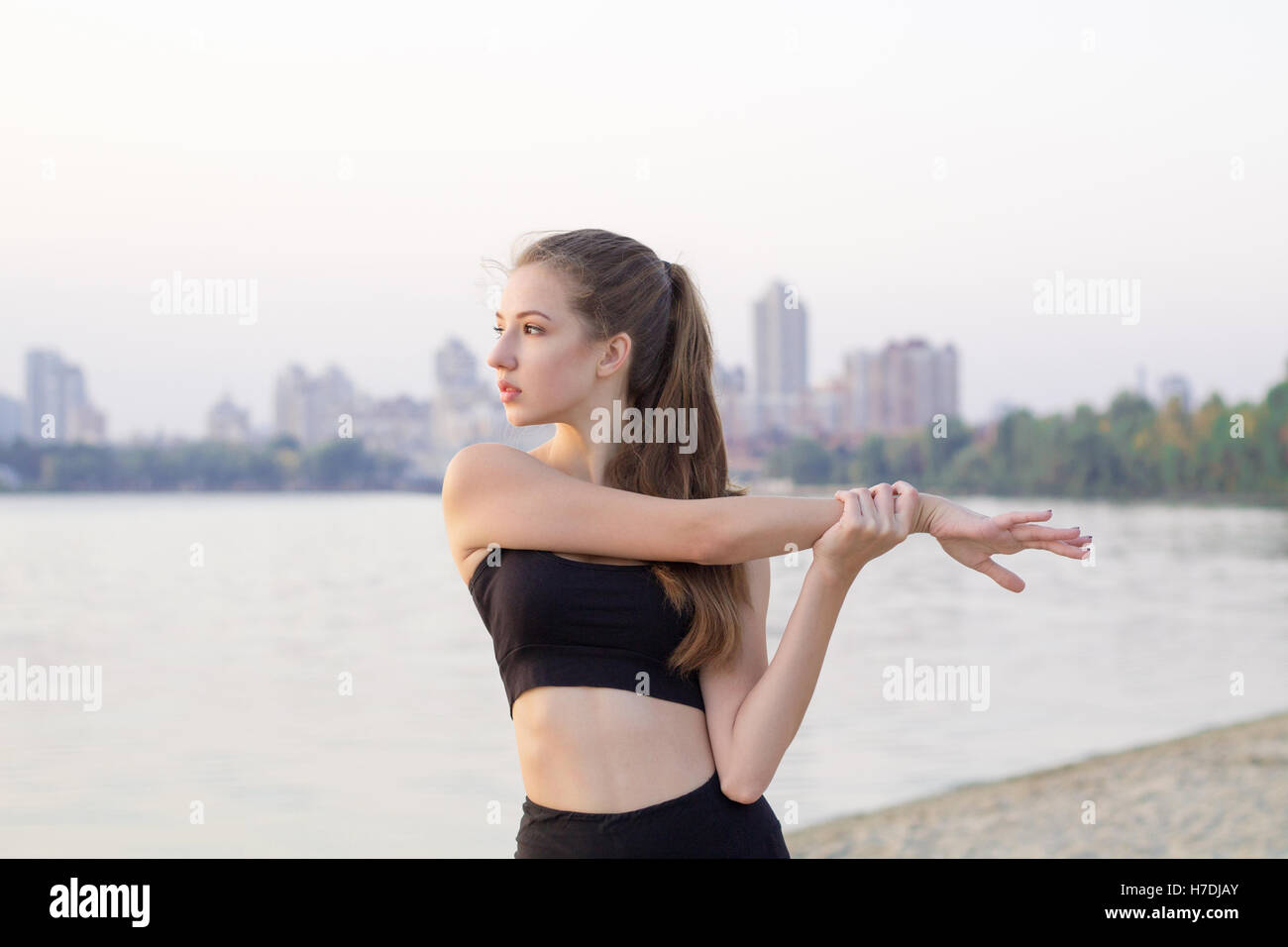 Jolie jeune femme sportive remise en forme slim s'étend de la préparation pour la formation exercices d'entraînement à l'extérieur de la côte de la rivière dans la matinée Banque D'Images