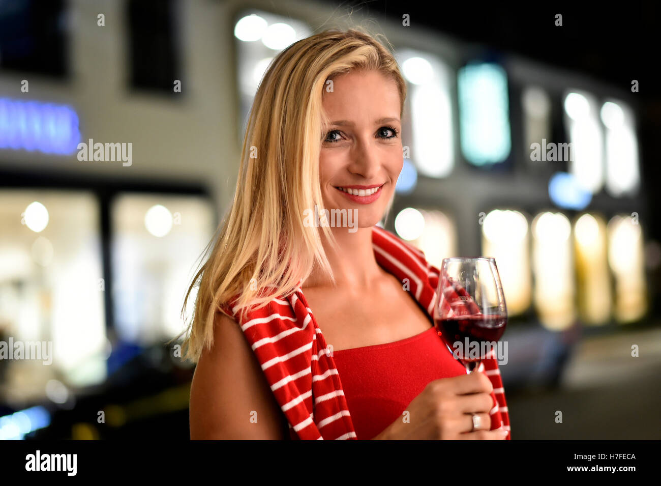 Femme avec un verre de vin dans sa main, dans la rue, la nuit, Allemagne Banque D'Images