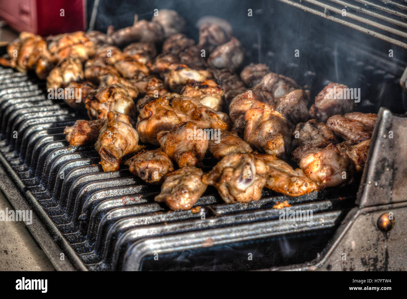Des ailes de poulet sur une chaude, smokey barbecue. L'accent délibéré et profondeur de champ pour l'effet. Banque D'Images