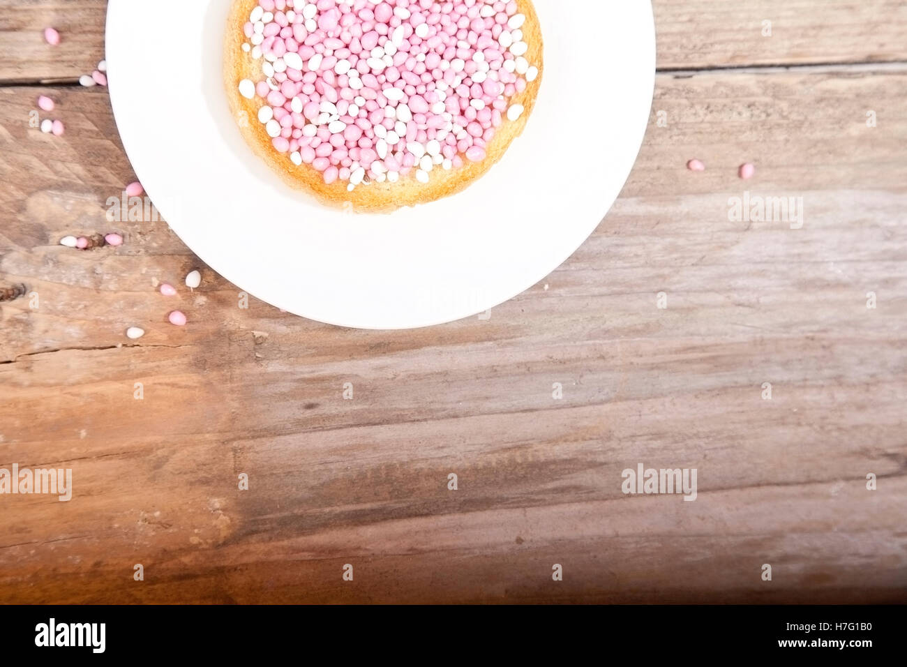 Célébration de naissance traditionnel néerlandais biscuit rose avec muisjes sur fond de bois Banque D'Images