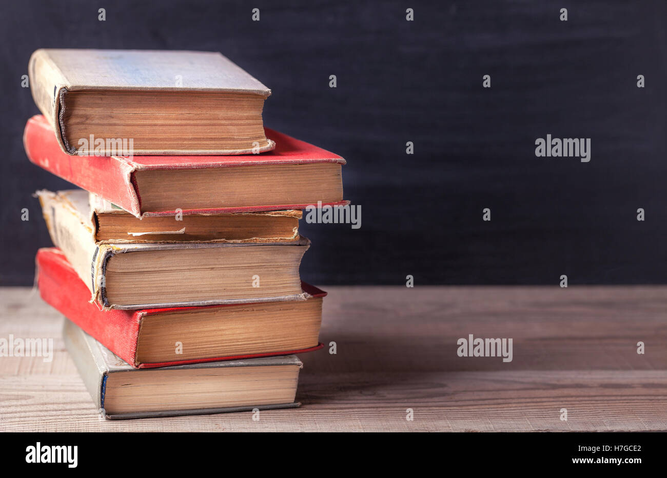 De vieux livres de cru sur une table rustique en bois noir sur fond de la commission scolaire. Close up Banque D'Images