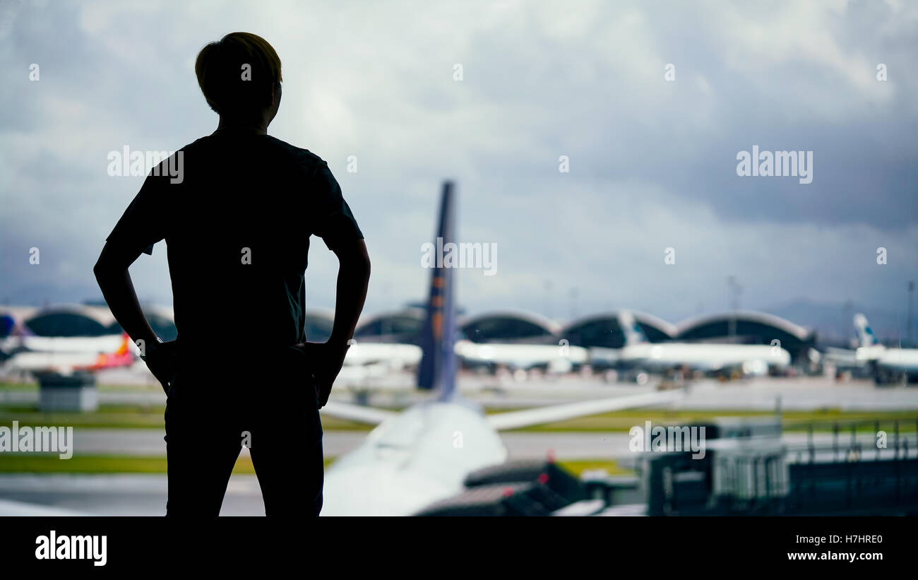 Un homme debout à l'avant-plan sur la silhouette floue d'arrière-plan de l'aéroport Banque D'Images