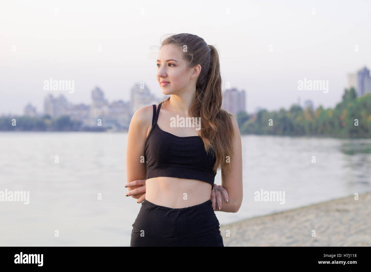 Jolie jeune femme sportive remise en forme mince et repose pendant la formation à l'extérieur pose des exercices d'entraînement à la côte de la rivière dans la matinée Banque D'Images