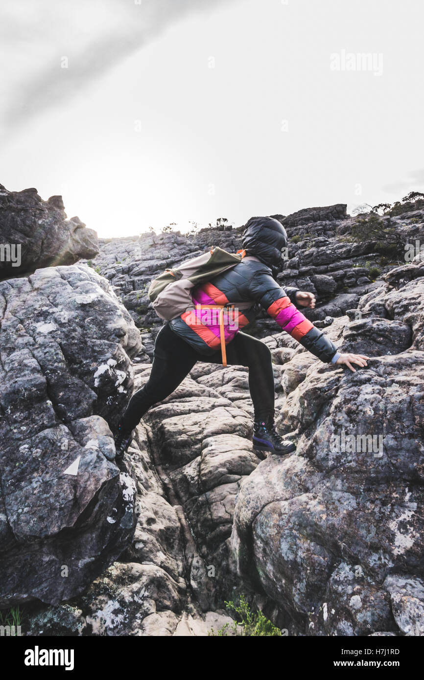 Girl in colorful Down jacket escalade rochers au lever du soleil dans le Parc National des Grampians, Victoria, Australie. Banque D'Images