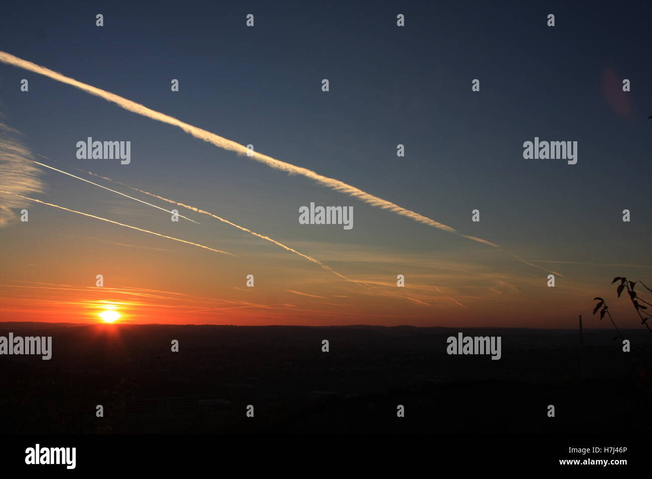 Traînées de jet sur le ciel bleu et le coucher du soleil Banque D'Images