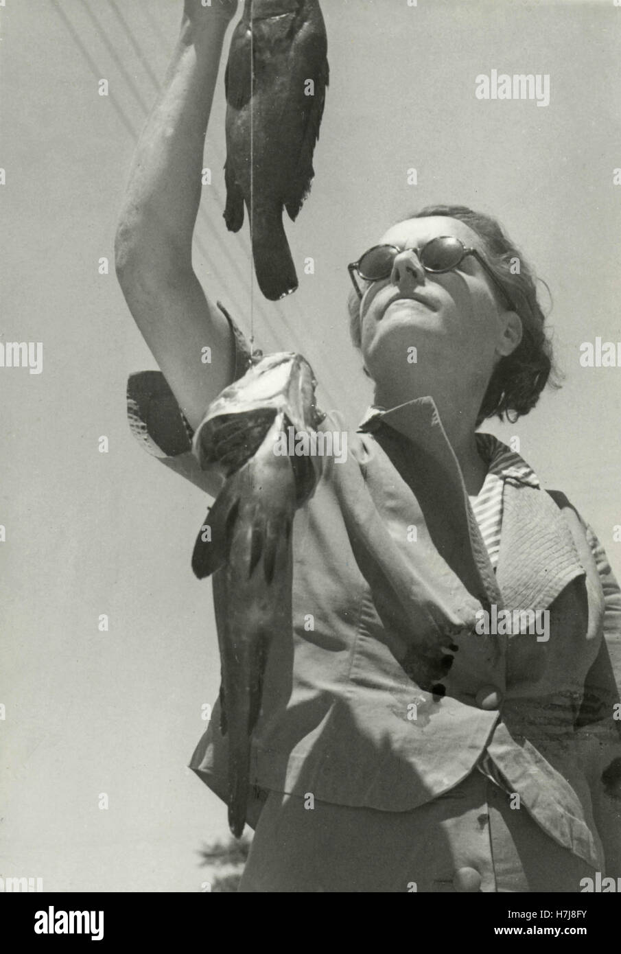 Pêcheuse montre deux mérous, Italie Banque D'Images