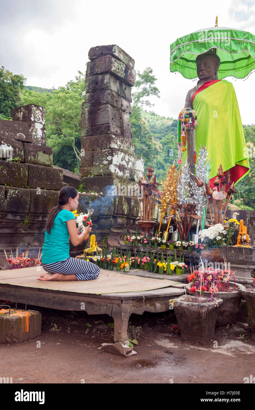Un dévot jette des fleurs au Wat Phu, les ruines d'un temple hindou Khmer dans complexe dans le sud du Laos Champassak. Banque D'Images