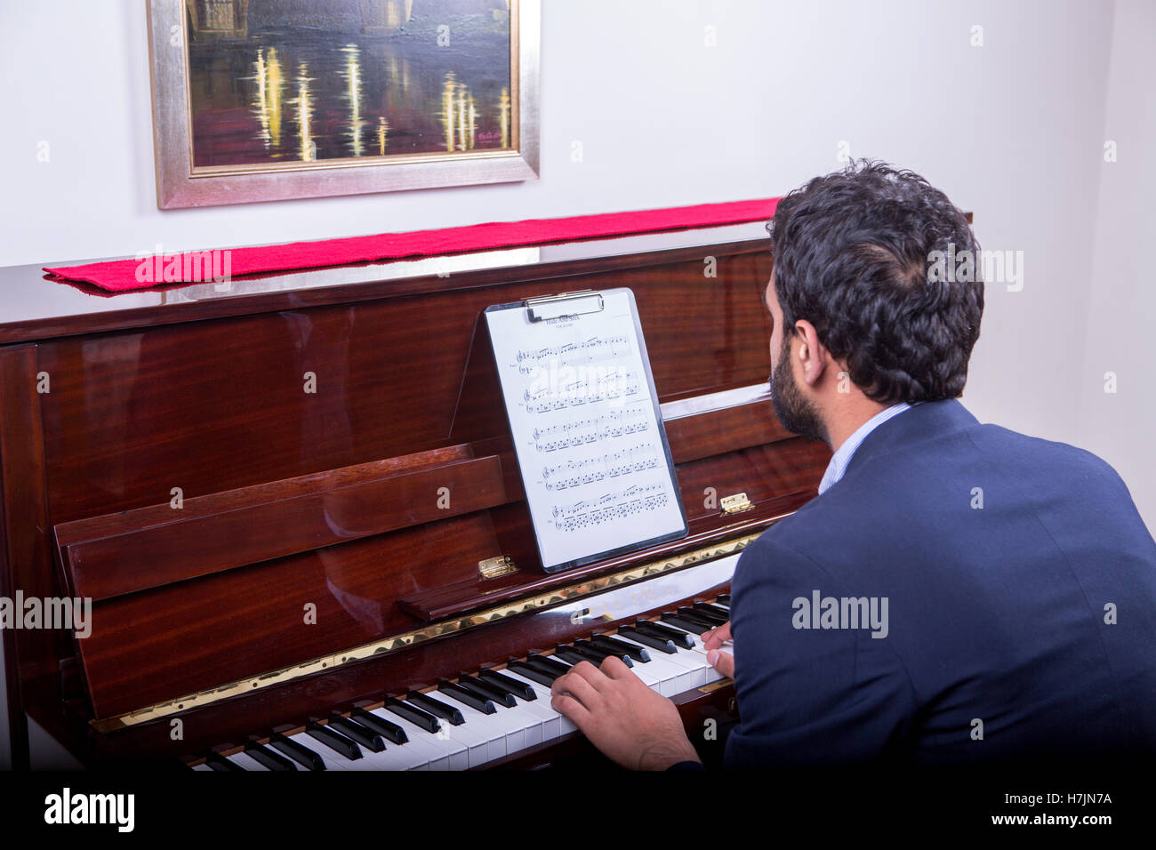 Man playing piano tune Baa Baa Black sheep, assis sur le fauteuil de lecture de notes Banque D'Images